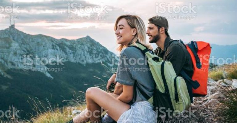 young couple of hikers enjoying the beautiful nature from high above